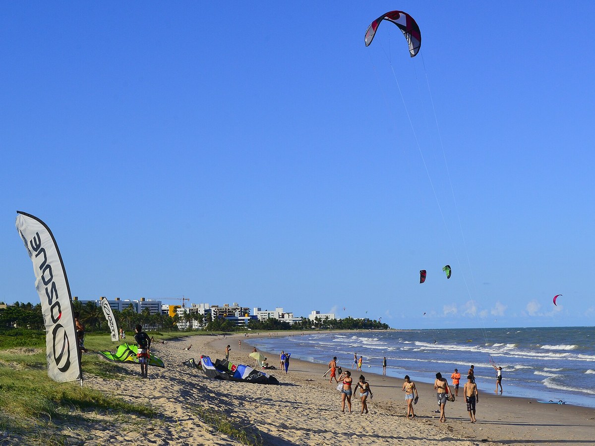 Praia de Intermares com praticantes de kitesurf e edifícios ao fundo
