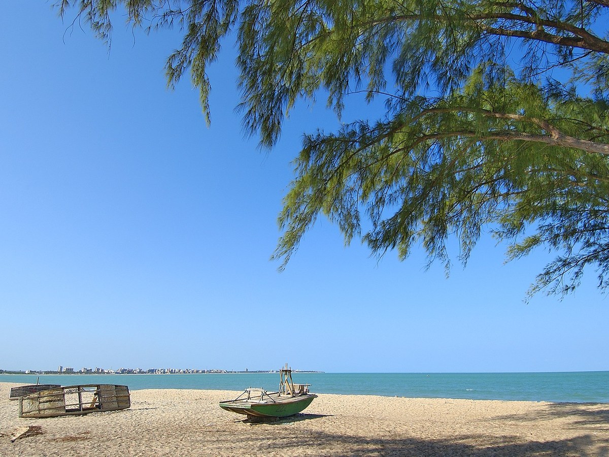 Praia do Bessa com faixa de areia, mar azul e barco de pesca
